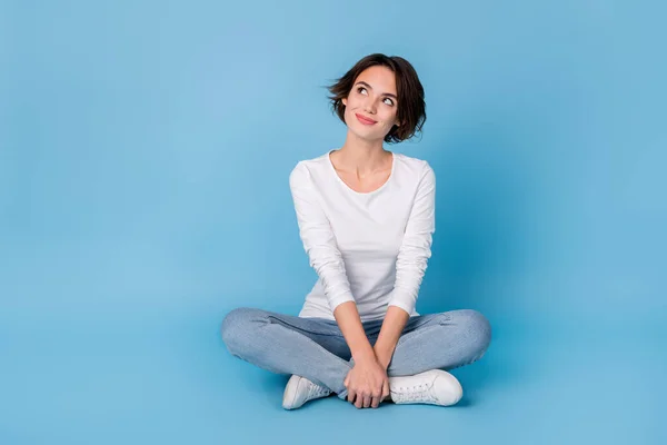 Foto de mujer bastante soñadora usar camisa blanca piernas sentadas cruzadas buscando espacio vacío aislado color azul fondo — Foto de Stock