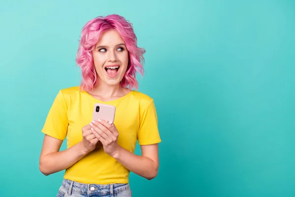 Foto de joven impresionado peinado rosa señora mantenga teléfono mirada espacio vacío desgaste camiseta amarilla aislada sobre fondo verde azulado — Foto de Stock