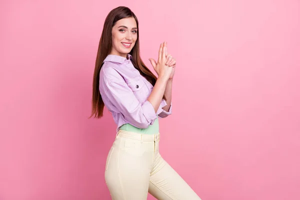 Foto retrato mulher sorrindo brincalhão mantendo dedos como arma isolado pastel cor-de-rosa fundo — Fotografia de Stock