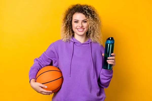 Fotografie mladé hezké dívky sportovní držení vody nápoj čerstvé cvičení držet míč izolované přes žlutou barvu pozadí — Stock fotografie