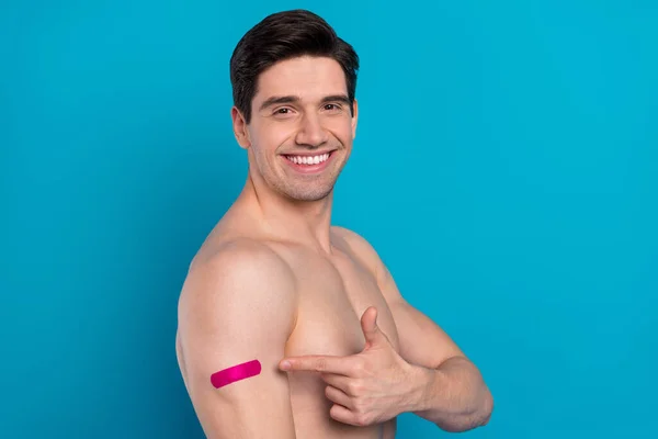 Photo of charming cheerful young guy topless smiling pointing finger vaccination patch isolated blue color background — Stock Photo, Image