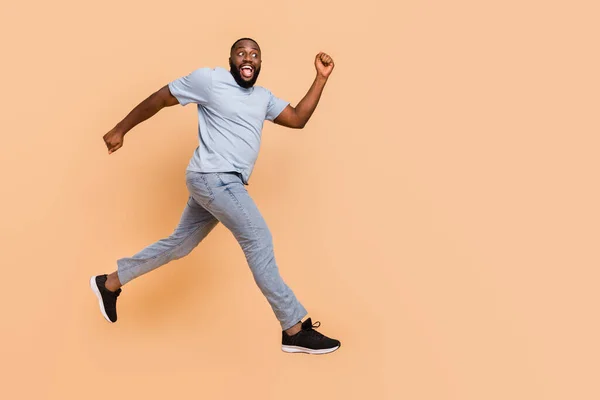 Full längd kroppsstorlek bild av attraktiv glad nyfiken kille hoppar kör isolerad över beige pastell färg bakgrund — Stockfoto