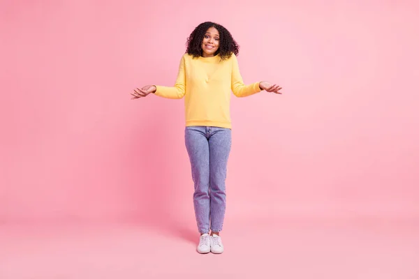 Photo de douce charmante fille de peau foncée habillée pullover jaune haussant les épaules souriant isolé fond de couleur rose — Photo