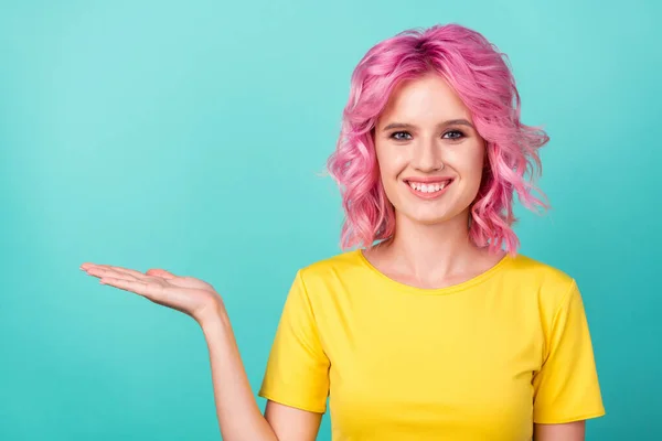 Foto de joven lindo peinado rosa lady hold espacio vacío desgaste camiseta amarilla aislada sobre fondo de color verde azulado — Foto de Stock