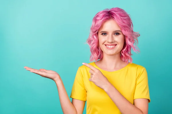 Foto de joven funky rosa peinado lady hold point espacio vacío desgaste camiseta amarilla aislada sobre fondo verde azulado — Foto de Stock