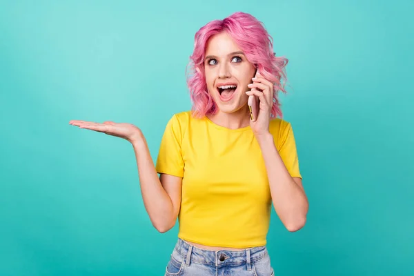 Foto van jong onder de indruk roze kapsel dame praten telefoon look lege ruimte dragen geel t-shirt geïsoleerd op teal achtergrond — Stockfoto