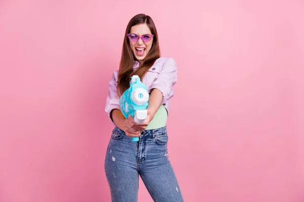 Фотопортрет женщина улыбается сверх радости в солнцезащитных очках игра держать пластиковый водяной пистолет изолированы пастельно-розовый цвет фона — стоковое фото