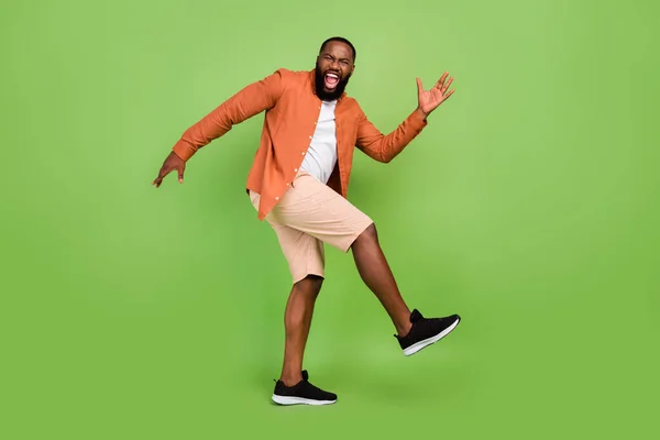 Full storlek foto av cool ung brunett kille dans bära skjorta shorts sneakers isolerad på grön färg bakgrund — Stockfoto