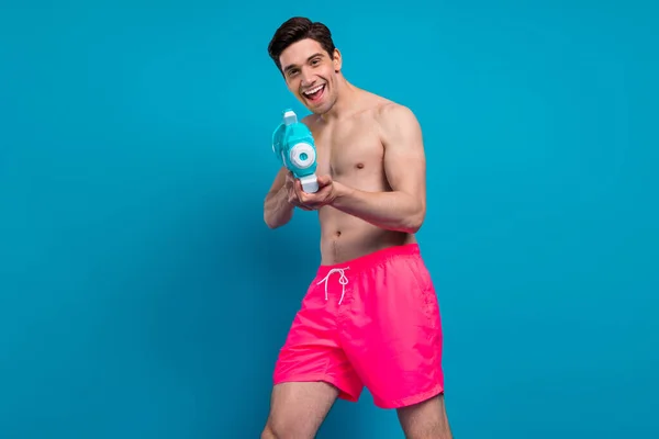 Foto pemuda menarik menawan tubuh telanjang tersenyum pistol air Terisolasi biru latar belakang warna — Stok Foto