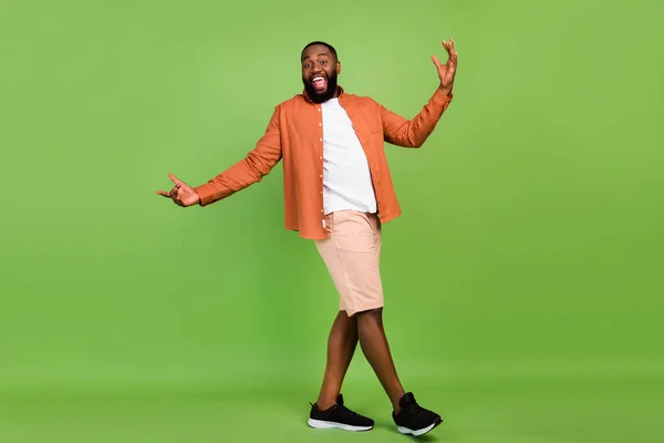 Full size foto van funky jonge brunet jongen dans dragen shirt shorts sneakers geïsoleerd op groene achtergrond — Stockfoto