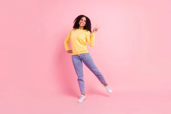 Foto de divertida encantadora mujer de piel oscura usar suéter amarillo que muestra v-signo aislado de color rosa fondo —  Fotos de Stock