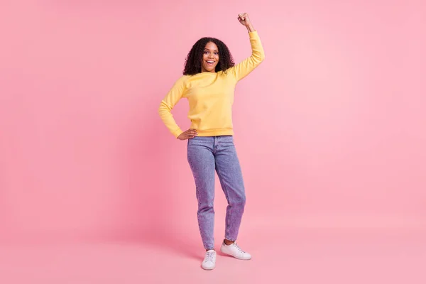 Foto de funky sorte mulher de pele escura usar amarelo sorrindo suéter levantando punho isolado cor rosa fundo — Fotografia de Stock