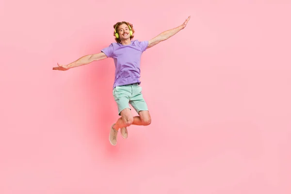 Volledige lichaamsomvang uitzicht van aantrekkelijke vrolijke funky man springen luisteren lied rust geïsoleerd over roze pastel kleur achtergrond — Stockfoto