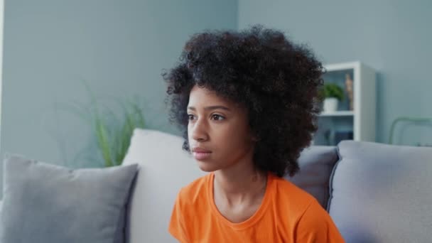 Испуганный ребенок сидит на диване и ест закуски триллер серии в помещении жилой комнаты — стоковое видео