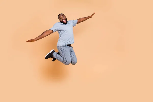 Plná délka tělo velikost pohled na atraktivní veselý chlap skákání létání s zábavou izolované přes béžové pastelové barvy pozadí — Stock fotografie