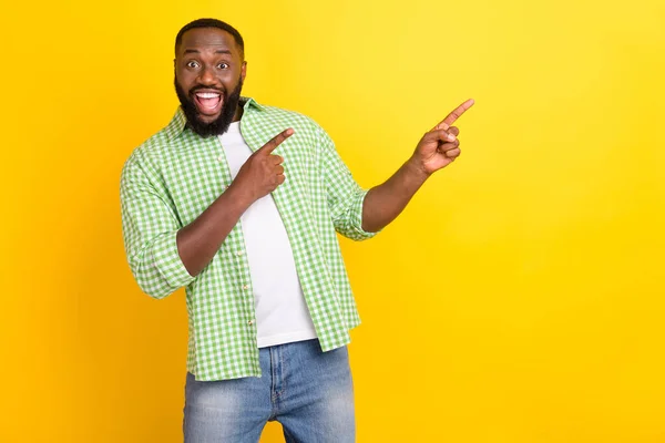 Photo of positive astonished guy indicate two finger empty space promotion isolated on yellow color background — Stock Photo, Image