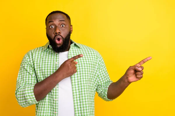 Portrait of handsome impressed person grimace reaction direct fingers empty space isolated on yellow color background — Stock Photo, Image