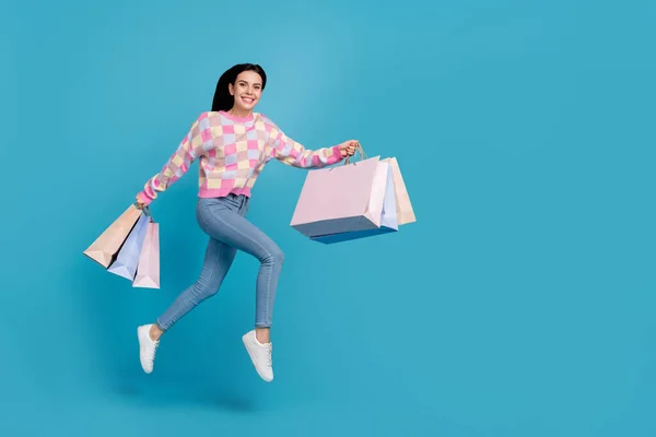 Foto van schattige schattige dame gekleed print trui springen holding tassen lege ruimte geïsoleerde blauwe kleur achtergrond — Stockfoto
