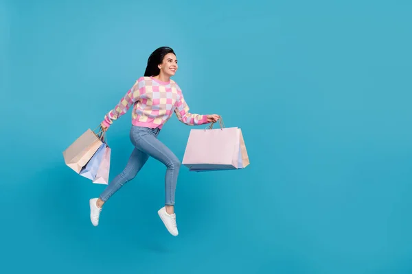 Foto de mujer dulce encantadora usar suéter rosa saltar celebración de gangas espacio vacío aislado color azul fondo —  Fotos de Stock