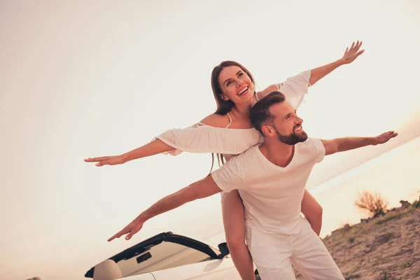 Foto di dolce divertente coppia di sposi vestiti di bianco guida auto in sella sorridente all'aperto strada di campagna — Foto Stock