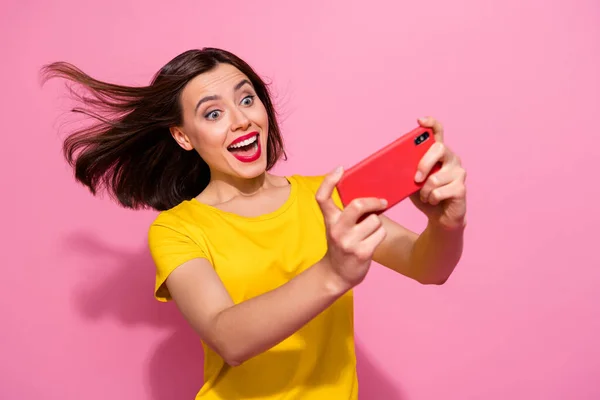 Портрет привабливої модної веселої дівчини, яка грає в веб-додаток гаджета, розважається ізольовано на рожевому пастельному кольоровому фоні — стокове фото