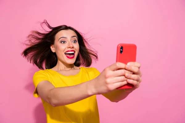 Фото враженої фанк молодої жінки в жовтому вбранні, що дме повітря, пишучи сучасний пристрій посміхаючись ізольований рожевий колір фону — стокове фото