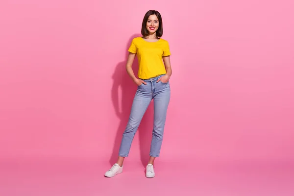 写真の面白いかわいい若い女性は黄色の服を着て歩く腕ポケット笑顔隔離されたピンク色の背景 — ストック写真