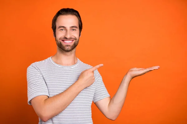 Foto de hombre joven indciate dedo producto proposición anunciar descuento aislado sobre fondo de color naranja — Foto de Stock