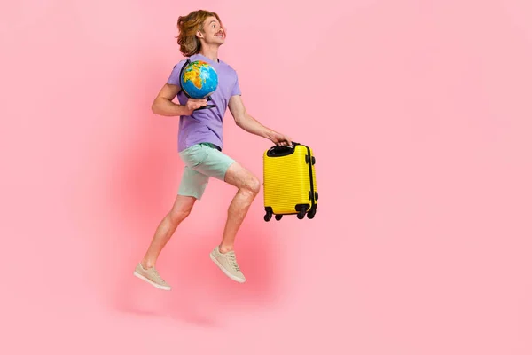 Full length body size view of attractive trendy cheery guy jumping carrying bag globe hurry tour isolated over pink pastel color background — Stock Photo, Image