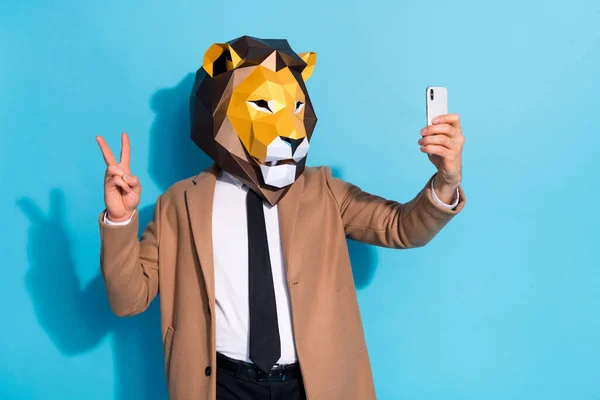 Foto de extraño tipo extraño en máscara de león tomando selfie teléfono inteligente hacer v-signo halloween evento aislado sobre fondo de color azul — Foto de Stock