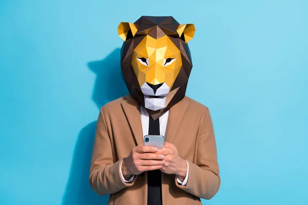 Foto de chico raro máscara de león uso de mensajes de texto de teléfono inteligente evento de Halloween invitar tema enviar aislado sobre fondo de color azul —  Fotos de Stock