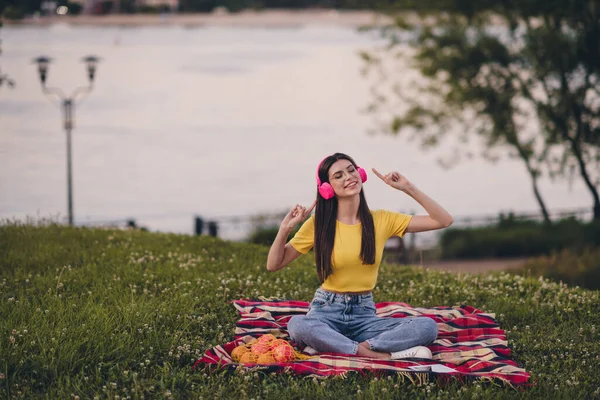 Ganzes Porträt positiver, funkiger Mensch, der auf karierter Decke sitzt und die Melodie der Playlist draußen genießt — Stockfoto