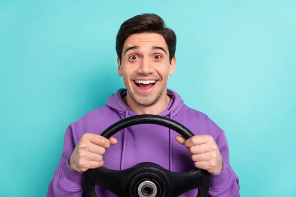 Retrato de bonito animado masculino equitação cartão segurar volante apreciando viagem de fim de semana isolado no fundo de cor azul — Fotografia de Stock