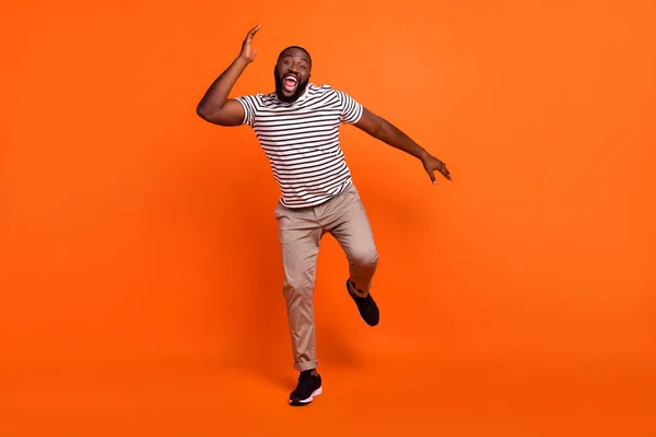 Полноразмерная фотография молодого возбужденного африканского мужчины с хорошим настроением на фоне оранжевого цвета — стоковое фото