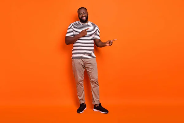Full tělo fotografie mladého afrického muže promotér indikovat prsty prázdný prostor rozhodnutí promo reklama izolované přes oranžové barvy pozadí — Stock fotografie