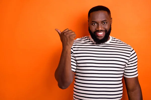Foto av ung afrikansk man indikerar tumme tomt utrymme proposition annonser välja isolerad över orange färg bakgrund — Stockfoto