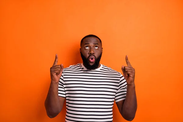 Фото молодого впечатленного африканца взгляд указывает на пальцы пустое пространство прямой способ рекламы баннер изолирован на оранжевый цвет фона — стоковое фото