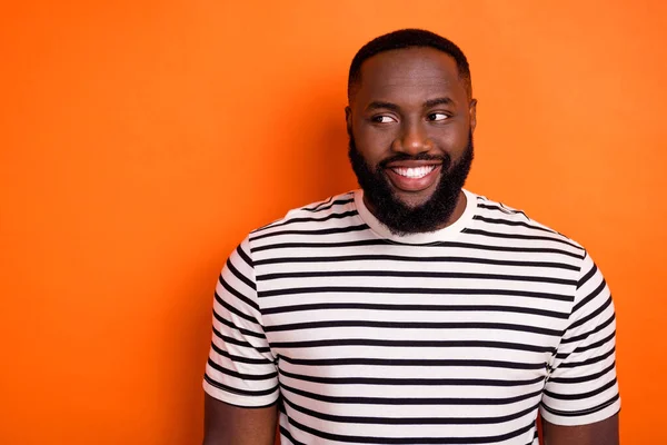 Foto van jonge vrolijke Afrikaanse man zich afgevraagd kijken lege ruimte denken geïsoleerd over oranje kleur achtergrond — Stockfoto