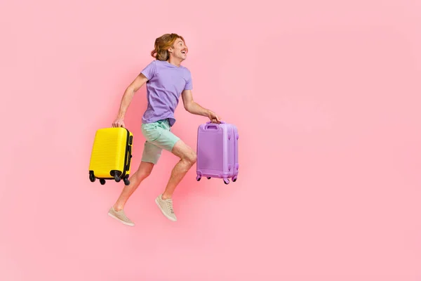 Plná délka tělo velikost pohled na atraktivní veselý chlap skákání držení tašky běží nízko nákladový let izolované přes růžové pastelové barvy pozadí — Stock fotografie