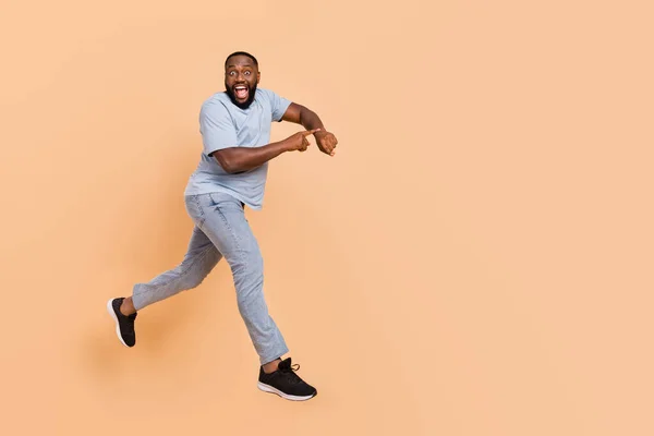 Longitud completa cuerpo tamaño vista de atractivo alegre chico saltando mostrando el tiempo corriendo aislado sobre beige pastel color fondo — Foto de Stock