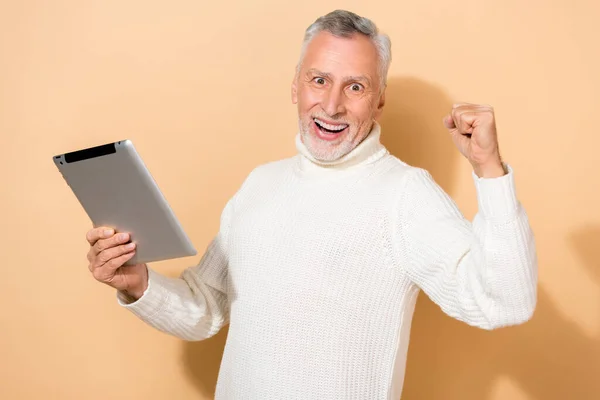 Portrait of attractive cheerful grey-haired man using gadget rejoicing having fun isolated over beige pastel color background — Stock Photo, Image
