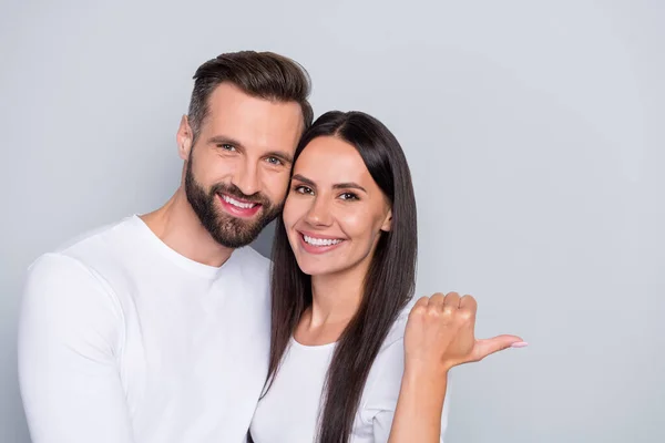 Portret atrakcyjnej wesołej pary przytulanie demonstrujące kopię puste miejsce reklama izolowane nad szarym pastelowym tle koloru — Zdjęcie stockowe