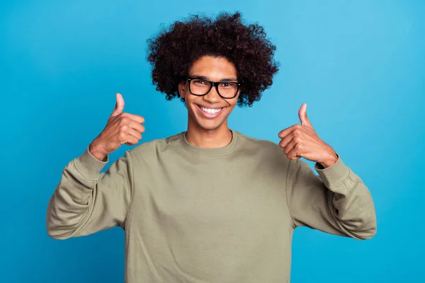 Photo de jeune homme joyeux montrer doigts pouces vers le haut approuver idéal parfait suggérer isolé sur fond de couleur bleue — Photo