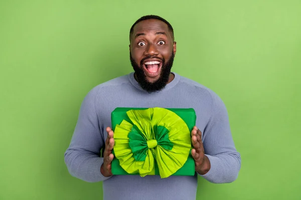 Fotografie dojem afro chlap nosit šedý svetr dostat dárek box s úsměvem izolované zelené pozadí — Stock fotografie