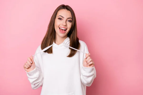 Fotografie mladé atraktivní dívka šťastný pozitivní úsměv držet tkaničky kapuce izolované přes růžové barvy pozadí — Stock fotografie