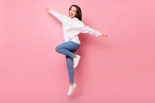 Foto de tamaño completo de fresco joven morena dama salto usar pantalones blancos con capucha aislados en el fondo de color rosa —  Fotos de Stock