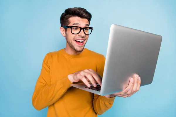 年轻人快乐的侧面照片积极的微笑聊天类型的电子邮件笔记本电脑隔离在蓝色背景下 — 图库照片