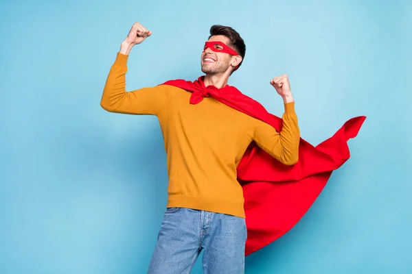 Foto de morena optimista joven héroe manos puños usan gafas suéter de capa aislado sobre fondo azul — Foto de Stock