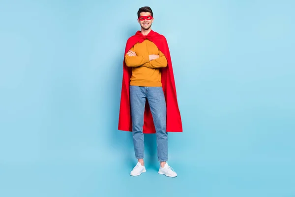 Fotografie roztomilé jistý mladý muž nosit žlutý svetr superman outfit usmívající se ruce složené izolované modré barvy pozadí — Stock fotografie