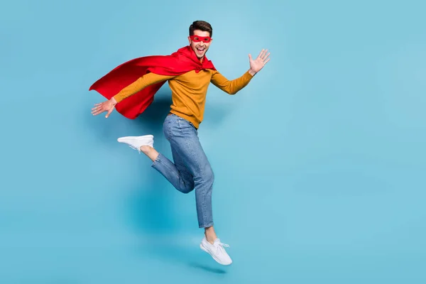 Foto de hombre joven apurado confiado usar traje de superman sonriendo saltando corriendo espacio vacío aislado color azul fondo —  Fotos de Stock